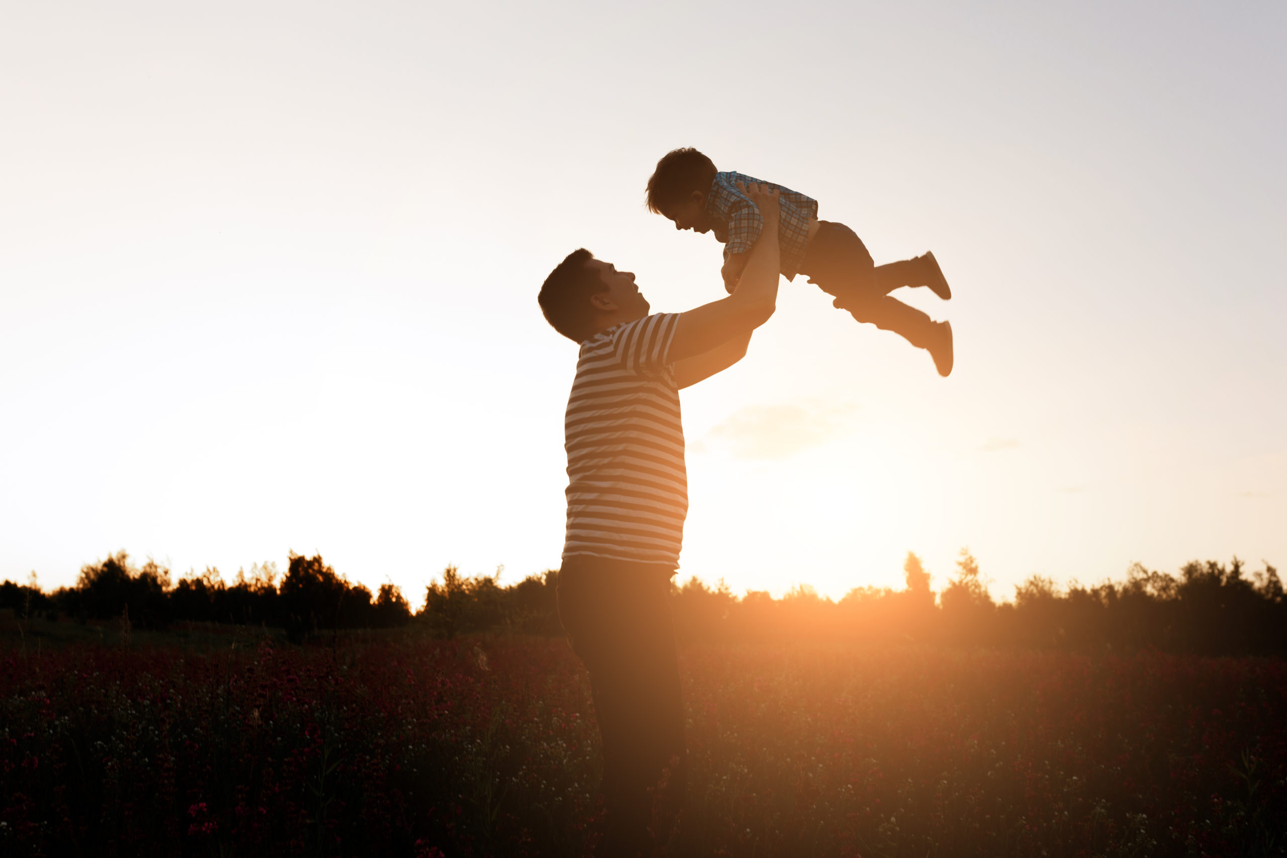 Father and son playing in the park at the sunset time. Happy family having fun outdoor